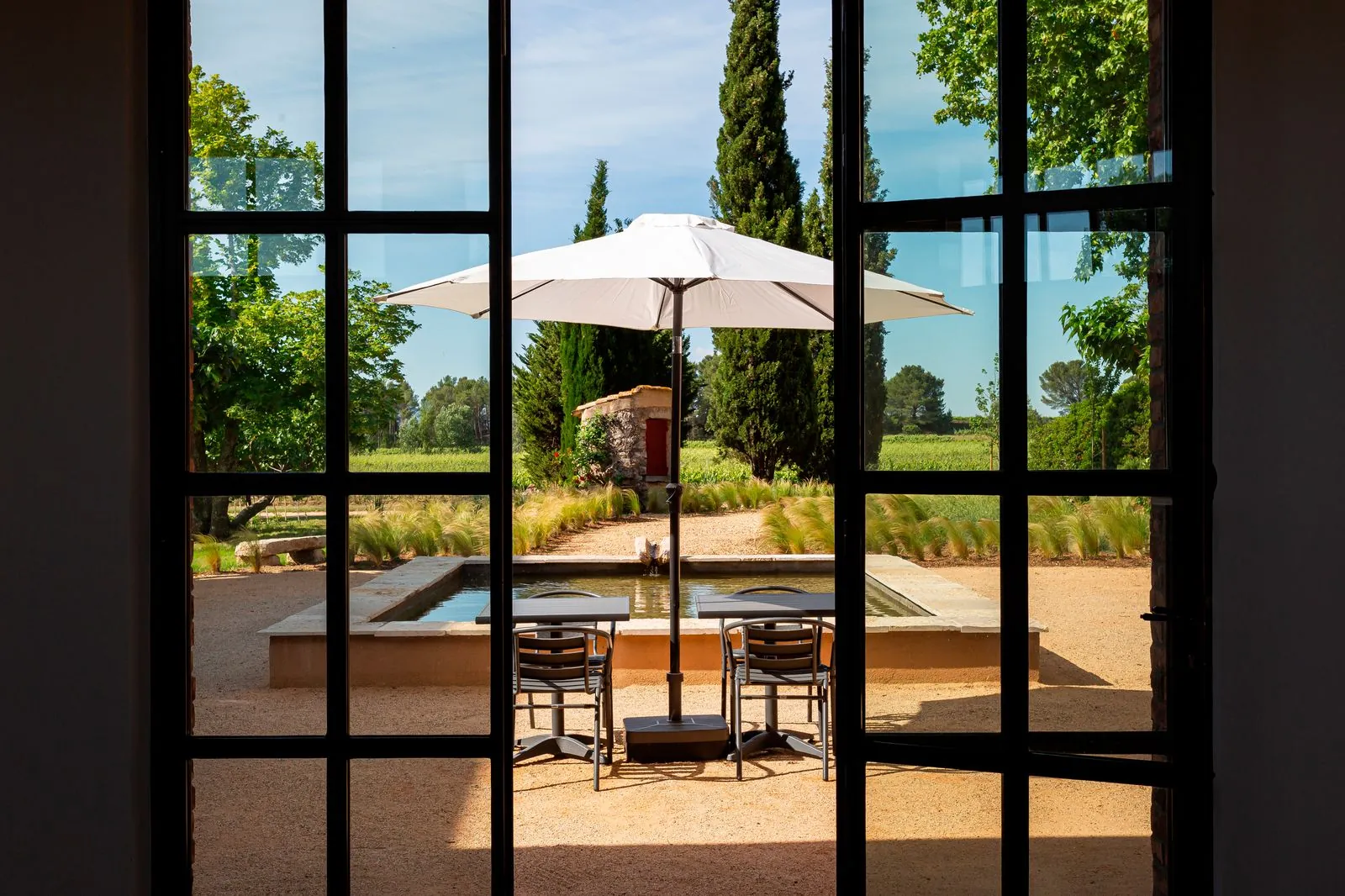 La terrasse et son parasol, vus à travers la baie vitrée du caveau